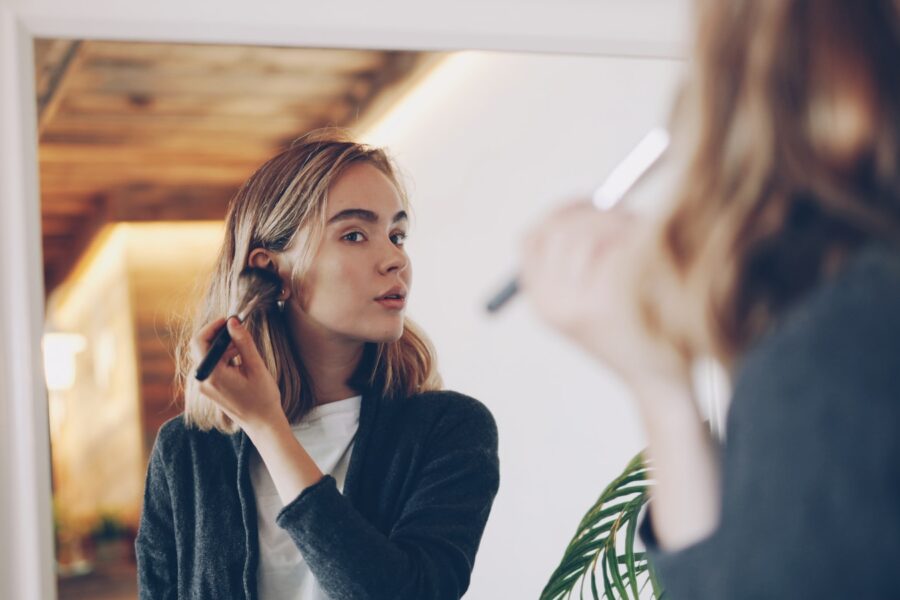 Nuomonės formuotoja filmuoja „get ready with me“ vaizdo įrašą ruošdamasi prie vonios veidrodžio