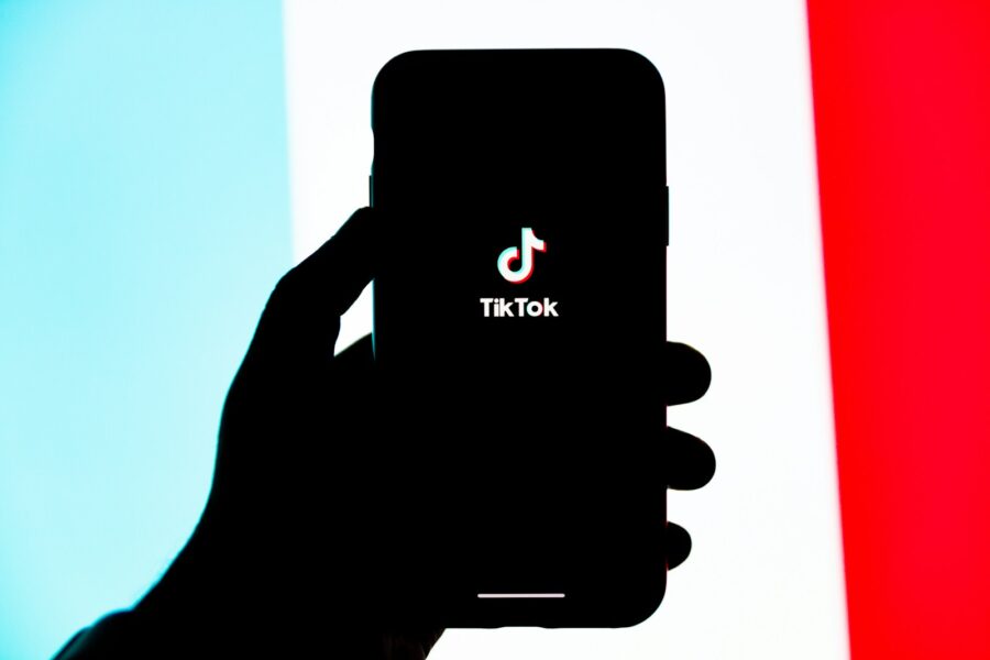 Išmanusis telefonas su atidaryta „TikTok“ programėle ir ausinės, simbolizuojančios naują dainų kūrimo erą