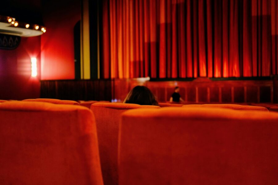Žiūrovai senoviškame kino teatre žiūri restauruotą klasikinį filmą dideliame ekrane