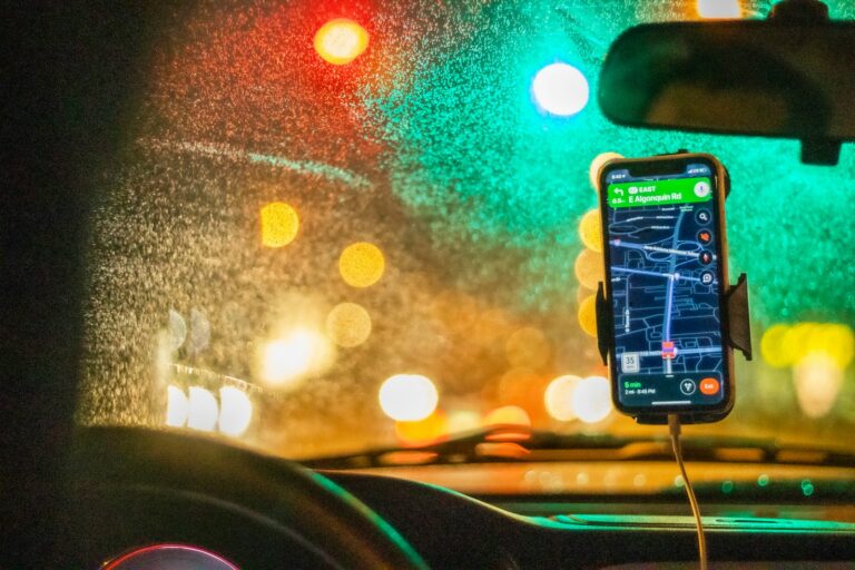 Vairuotojas naktį žvilgteli į telefone veikiančią GPS žemėlapio programėlę